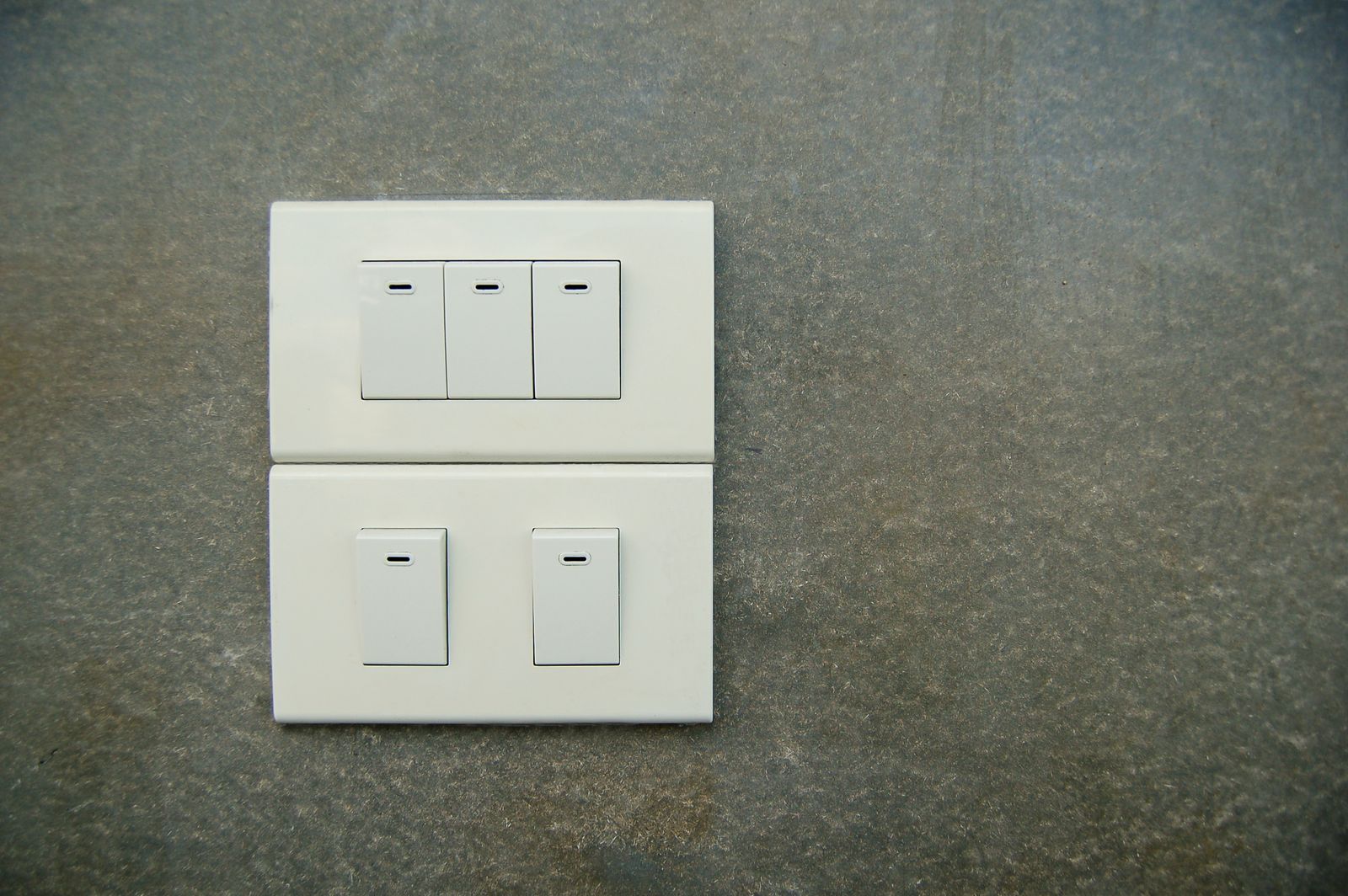 Sample image of white rocker light switches on a grey stone wall